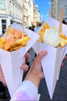 two people holding up paper cones with food in them