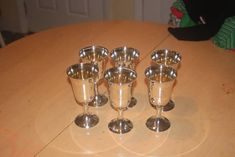 six silver cups sitting on top of a wooden table