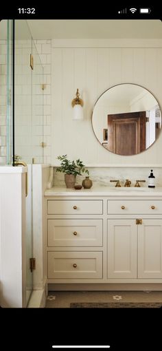 a bathroom with white cabinets and a large round mirror