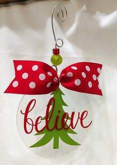 a glass ornament with a red bow and white polka dots on it that says believe