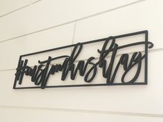 a metal sign that says happy birthday hanging on the side of a white building with black lettering