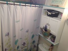 a bathroom with a shower curtain, toilet and sink in it's corner area