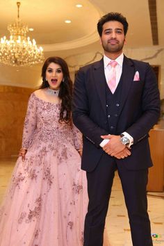 a man and woman standing next to each other in front of a chandelier