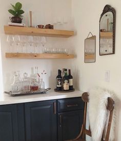 there is a bar with wine glasses and bottles on the shelves above it in this kitchen