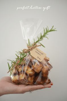 a hand holding a bag of cookies with rosemary sprigs on it and a label that says, perfect selection gift