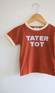 Introducing Tator Tot Kids Ringer: the perfect choice for the little ones in your life. Made with 100% organic cotton, this polished printed ringer is pre-shrunk and true to size. Let your tots stand out with this exclusive Tater Tot design. Tator Tots, Boys Clothing, Tater Tot, Hang Tags, Sew-in Labels, Need This, We Need, Boy's Clothing, Gender Neutral