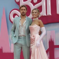 a man and woman standing next to each other in front of a pink sign that says ball