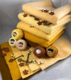 a pile of yellow towels sitting on top of a white table next to spools of thread