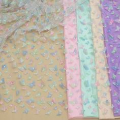 several different colored butterflies are on the table next to some sheer fabric and tulle