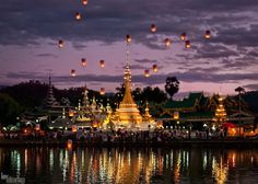 many lanterns floating in the air over water