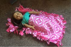 a doll laying on top of a pink and white blanket covered in ruffles