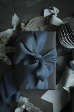 a gift wrapped in blue and white paper with a bow on the top, surrounded by other decorative items