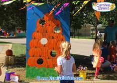 several children are standing in front of a painted pumpkin house with balloons and streamers