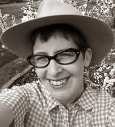 a man wearing glasses and a hat taking a selfie in front of some flowers