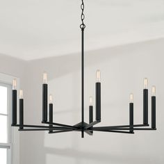 a black chandelier hanging from a ceiling in a room with white walls and windows