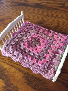 a crocheted blanket is laying on top of a doll's rocking chair