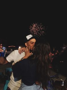 two people kissing each other with fireworks in the background