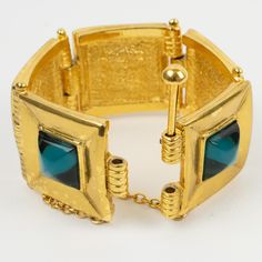 This lovely Jean Louis Scherrer Paris link bangle bracelet features a geometric shape in shiny metal ornate with resin cabochons in transparent turqu… Modern Metal Hinged Jewelry, Luxury Metal Jewelry With Box Clasp, Gold Metal Bracelets With Cabochon, Gold Metal Bracelet With Cabochon, Metal Cabochon Bracelet, Formal Turquoise Bangle Jewelry, Formal Turquoise Bangle Bracelet, Turquoise Bangle Bracelet For Formal Occasions, Turquoise Bangle For Formal Occasions