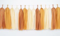 several tassels hanging from a line on a white wall with one orange and the other yellow