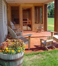 two wooden chairs sitting on top of a porch next to a potted planter