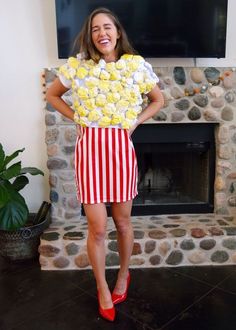 a woman standing in front of a fire place with flowers on her shirt and red shoes