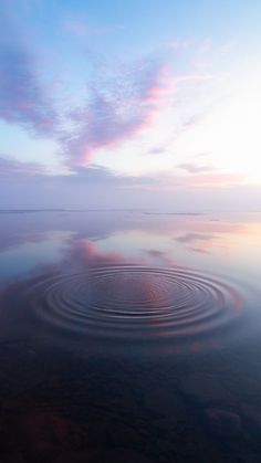 a large body of water surrounded by land and clouds in the distance, with a circular design on it's surface