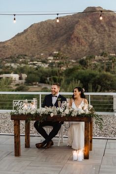 a bride and groom sitting at a table with candles