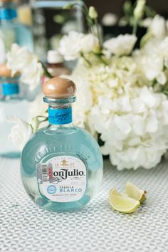 a bottle of gin is sitting on a table with flowers and lemons in the background