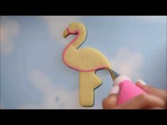 someone is decorating a flamingo shaped cookie