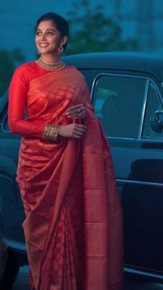 a woman in a red sari standing next to a car