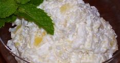 a close up of a bowl of food with green leaves on the table next to it