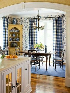 an archway leads into a dining room with blue and white wallpaper on the walls