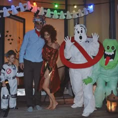 a man and woman standing next to two children dressed up as ghost, monster and alien