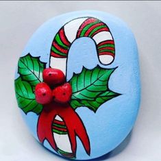 a painted rock with holly and candy canes on it