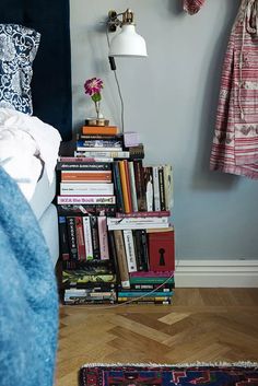 a bookshelf filled with lots of books in front of a blue wall next to a bed