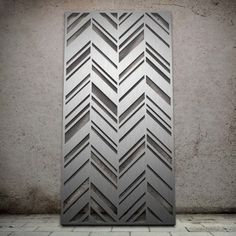 a metal door with an arrow pattern on it in front of a brick floor and wall