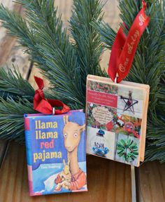 two christmas ornaments are sitting on a table next to some pine branches and red ribbon