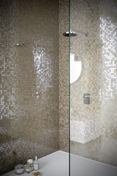 a bathroom with a glass shower door and tiled walls in the shower area is shown