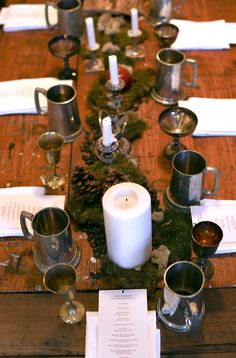 the table is set with silver cups and candles