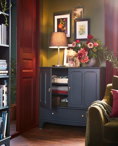 a living room filled with furniture and flowers on top of a book shelf in front of a doorway