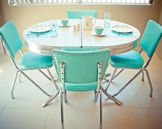 a white table topped with blue chairs next to a window