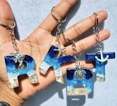 a hand holding three pieces of glass that spell out the word pride and an anchor