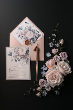 the wedding stationery is laid out on top of the table with flowers and a pen