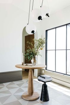 a room with a table and some lights hanging from it's ceiling, next to a large window