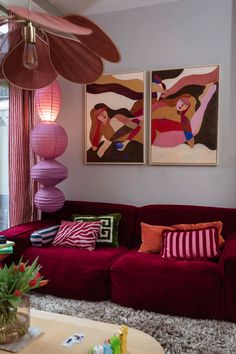 a living room with red couches and paintings on the wall