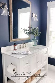 a bathroom with blue walls and white cabinets, a mirror over the sink, and a wicker basket on the floor