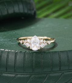 an engagement ring with three stones on top of green leather seat cushioned surface next to tire