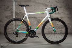 a white and green bike parked in front of a cement wall