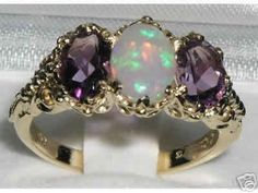 This ring is made from Solid 750 18ct 18K Yellow Gold with Natural Semi-precious Opal & Amethysts.*Total gemstone weight :Opal 0.75ct, Amethyst  1.5ctOne Center 8x6 mm (0.32" x 0.24") Opal and two 7x5 mm (0.28" x 0.20") Beautiful Vibrant Amethysts oval cut set in a Solid Yellow Gold Antique / Victorian style prong setting. This ring has a good solid feel, a nice weight and a good thick shank.*Total Height 5mm, Width 16mm, Length 11mm Solid English 18K Gold - on the inside of the shank there Trilogy Ring, Precious Opal, Carved Ring, Natural Opal, Anniversary Ring, Amethyst Ring, Pink Tourmaline, Victorian Fashion, Anniversary Rings