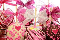 chocolate covered candies with pink bows and hearts on them sitting in front of candy sticks